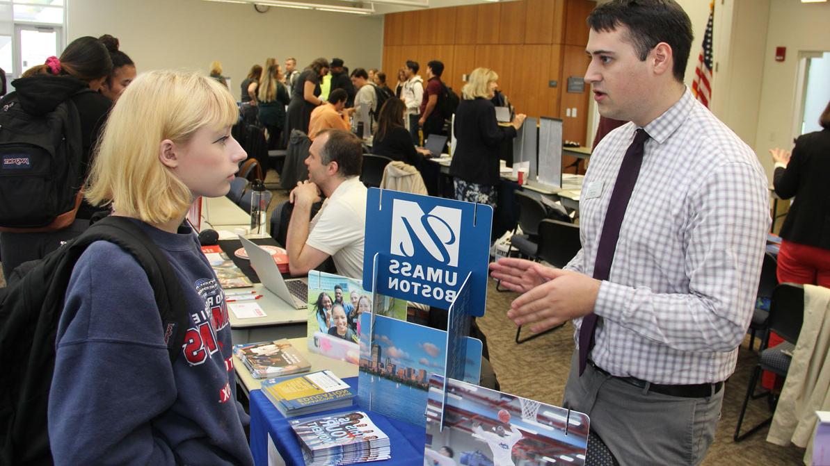 一名女学生在韦德买球网站年度转学博览会上与麻省大学波士顿分校的代表交谈. 